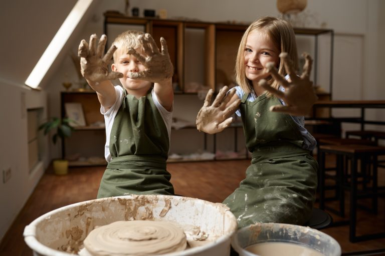 Des enfants montrent leurs mains couvertes d'argile, des enfants dans un atelier